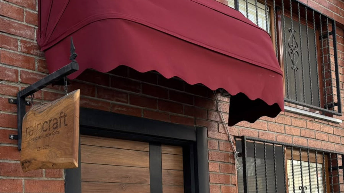 RainCraft atölyesinin kapısı, üzerinde ahşap "raincraft EST. 2019" tabelası ve bordo tente